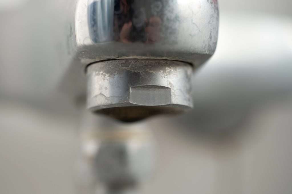 A bathroom sink fixture with hard water stains.