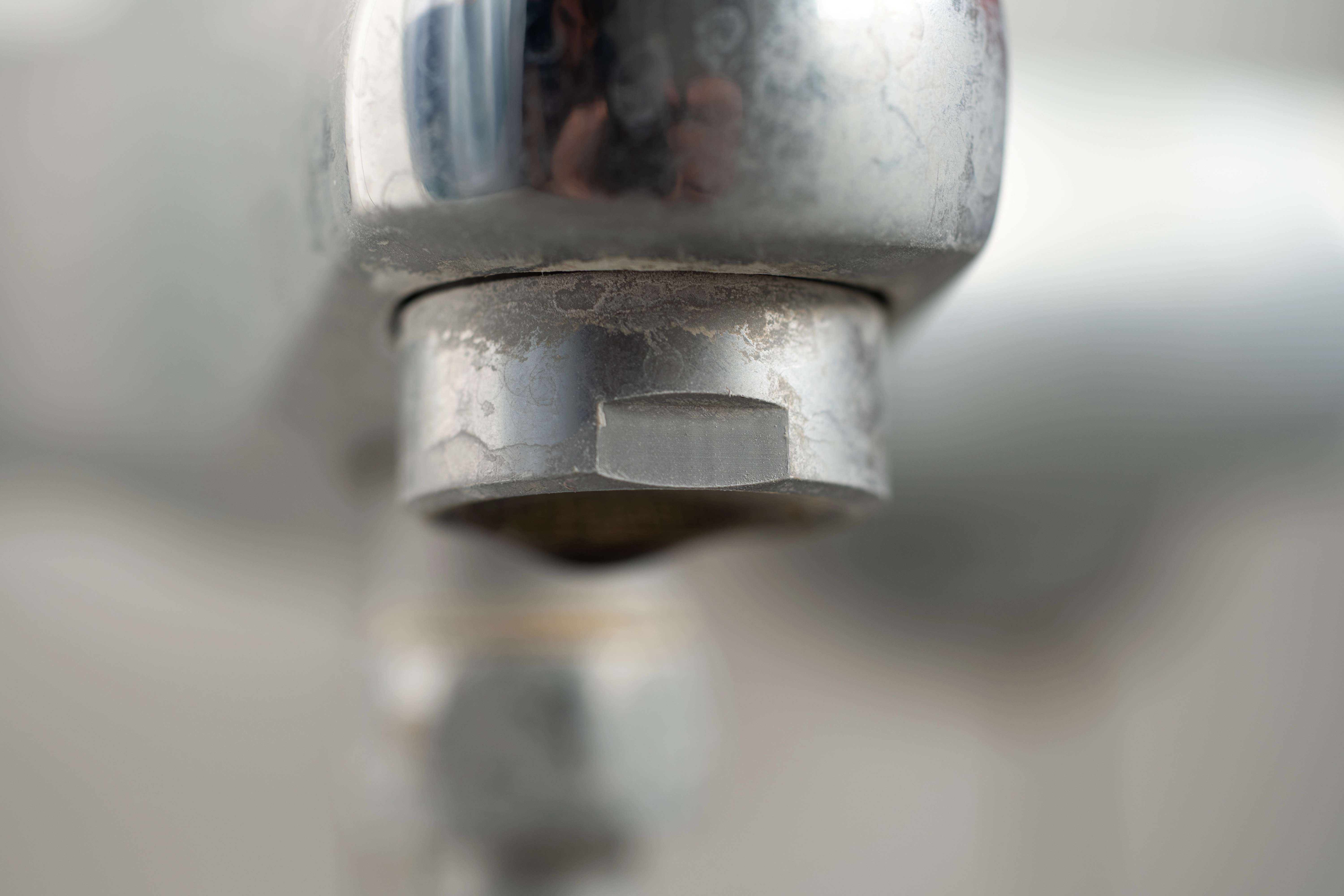 A bathroom sink fixture with hard water stains.