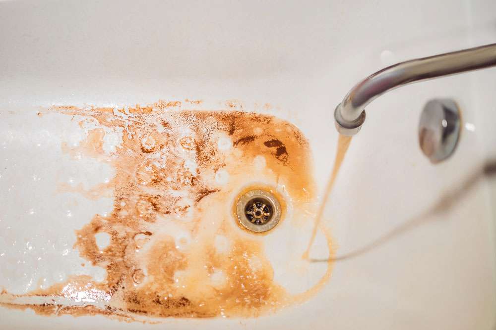A bathtub stained with iron residue from hard tap water