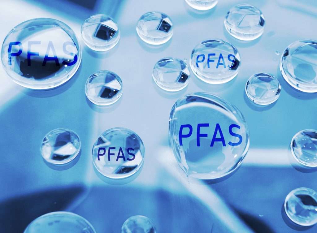 Close-up illustration of clear water droplets with the text “PFAS” inside, symbolizing PFAS contamination in water.