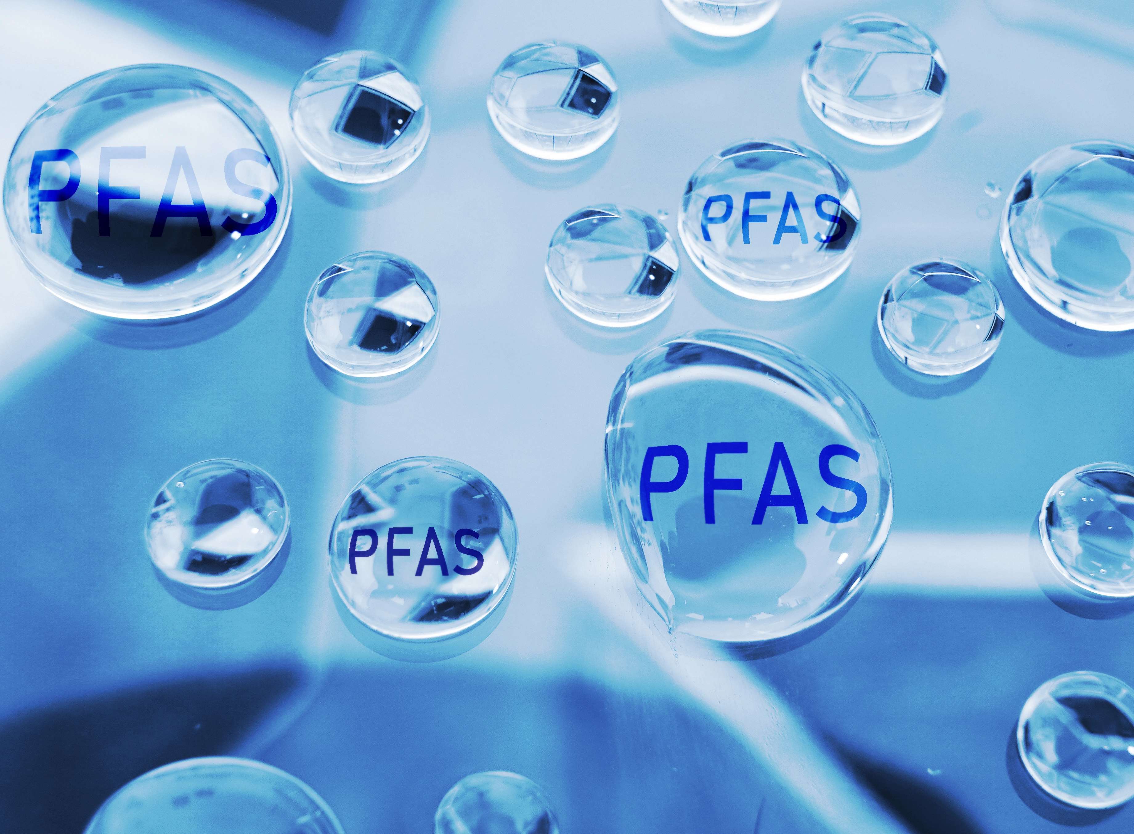 Close-up illustration of clear water droplets with the text “PFAS” inside, symbolizing PFAS contamination in water.